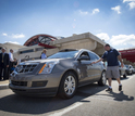 People standing next to parked Cadillac SRX  driverless car